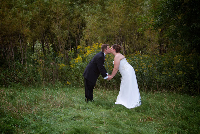 Outdoor portrait of bride and groom stooped over to kiss each other