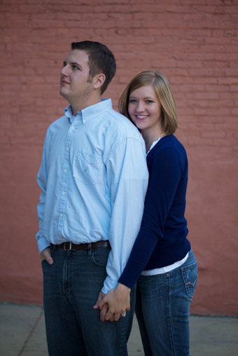 Engaged couple in front of brick wall
